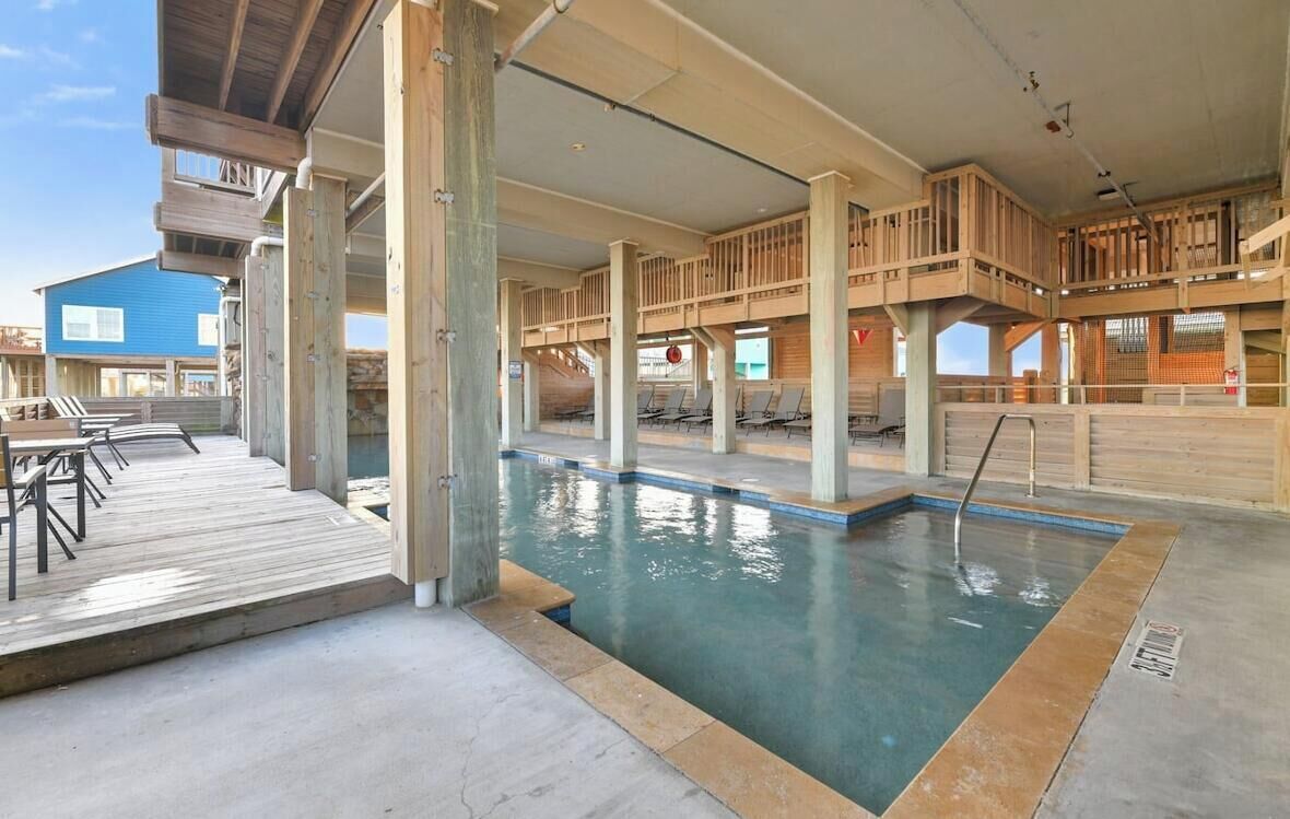 A pool area with wooden deck seating and a clear view of the pool.