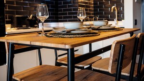 Eine moderne Küche mit einem Holztisch, gedeckt für zwei Personen, mit Schüssel, Weingläsern und Besteck.