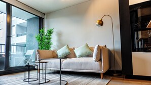 Ein modernes Wohnzimmer mit Sofa, Couchtisch, Stehlampe und einem großen Fenster.