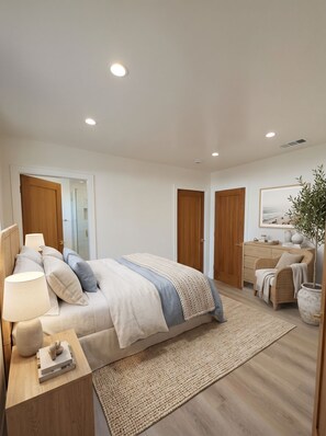 A modern bedroom with a bed, bedside tables, a nightstand, a large window, and a door. - Bluff Park Oasis (Long Beach)