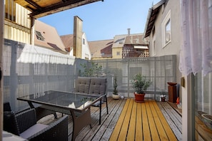 A patio area with a glass table, wicker chairs, and potted plants. - Pet-Friendly Apartment in Historic Tanner’s House with Private Terrace in the Allgäu (Memmingen)