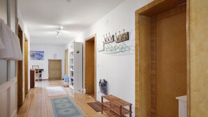 Un pasillo con suelo de madera, un banco, un perchero y una puerta.