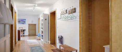 A hallway with wooden flooring, a bench, a coat rack, and a door.
