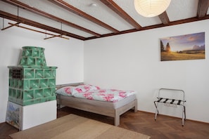 A bedroom with a bed, a green storage unit, a painting, and a metal chair. - Pet-Friendly Apartment in Historic Tanner’s House with Private Terrace in the Allgäu (Memmingen)