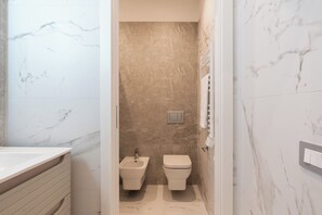 Een badkamer met een marmeren wastafel, een bidet en een toilet.