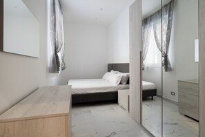 Een moderne slaapkamer met een bed, nachtkastje en spiegel.