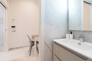 Ein modernes Badezimmer mit Marmorwaschbecken, einem großen Spiegel und einer Toilette.