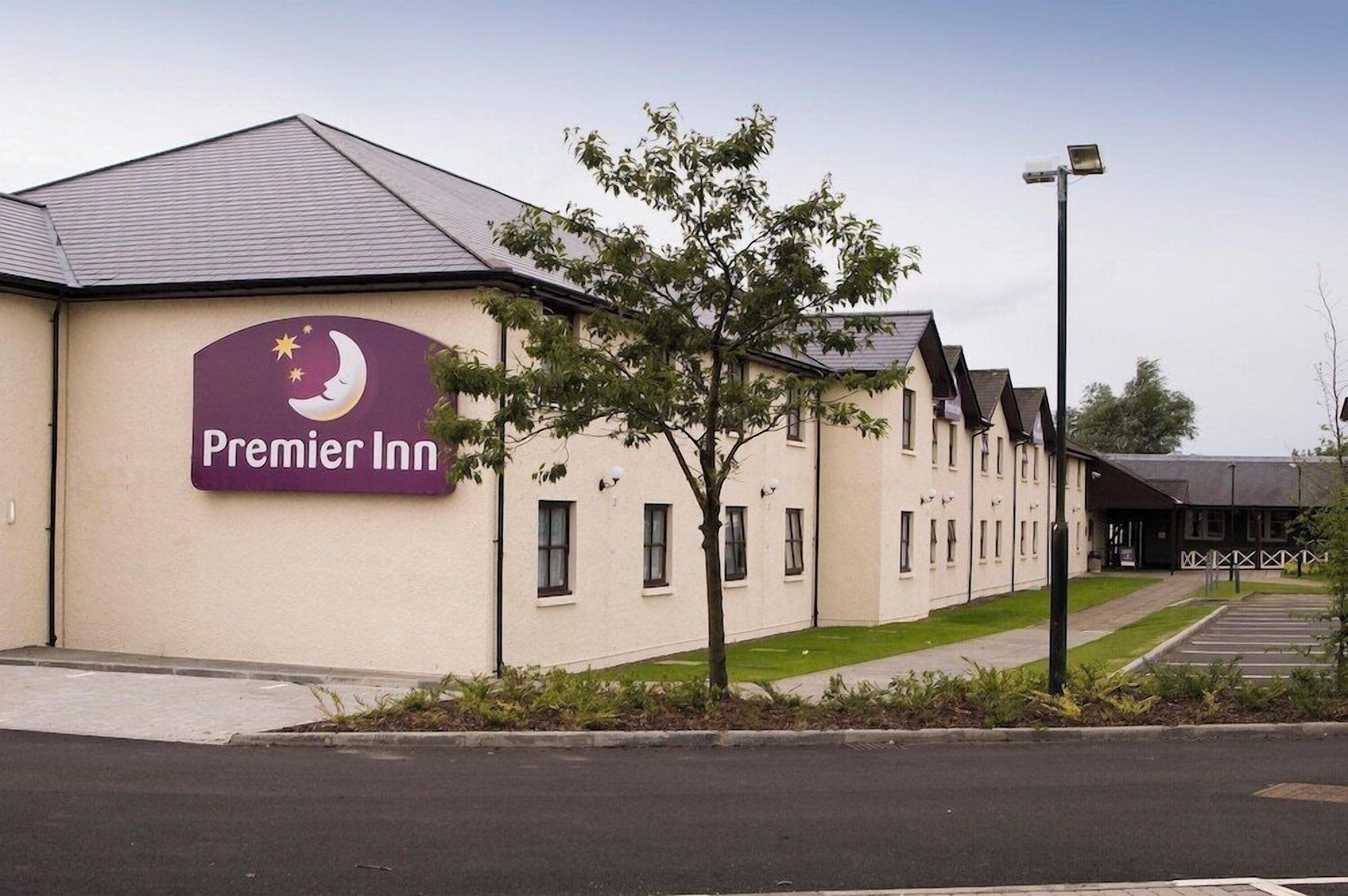 A hotel with a sign reading 'Premier Inn' and a parking lot in front.