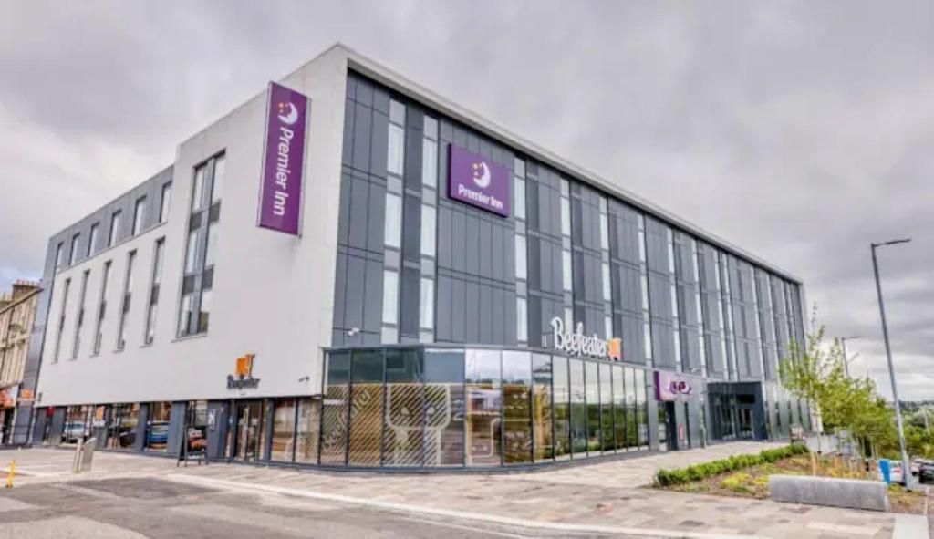 A modern hotel building with a prominent Premier Inn logo, large windows, and a clean facade.