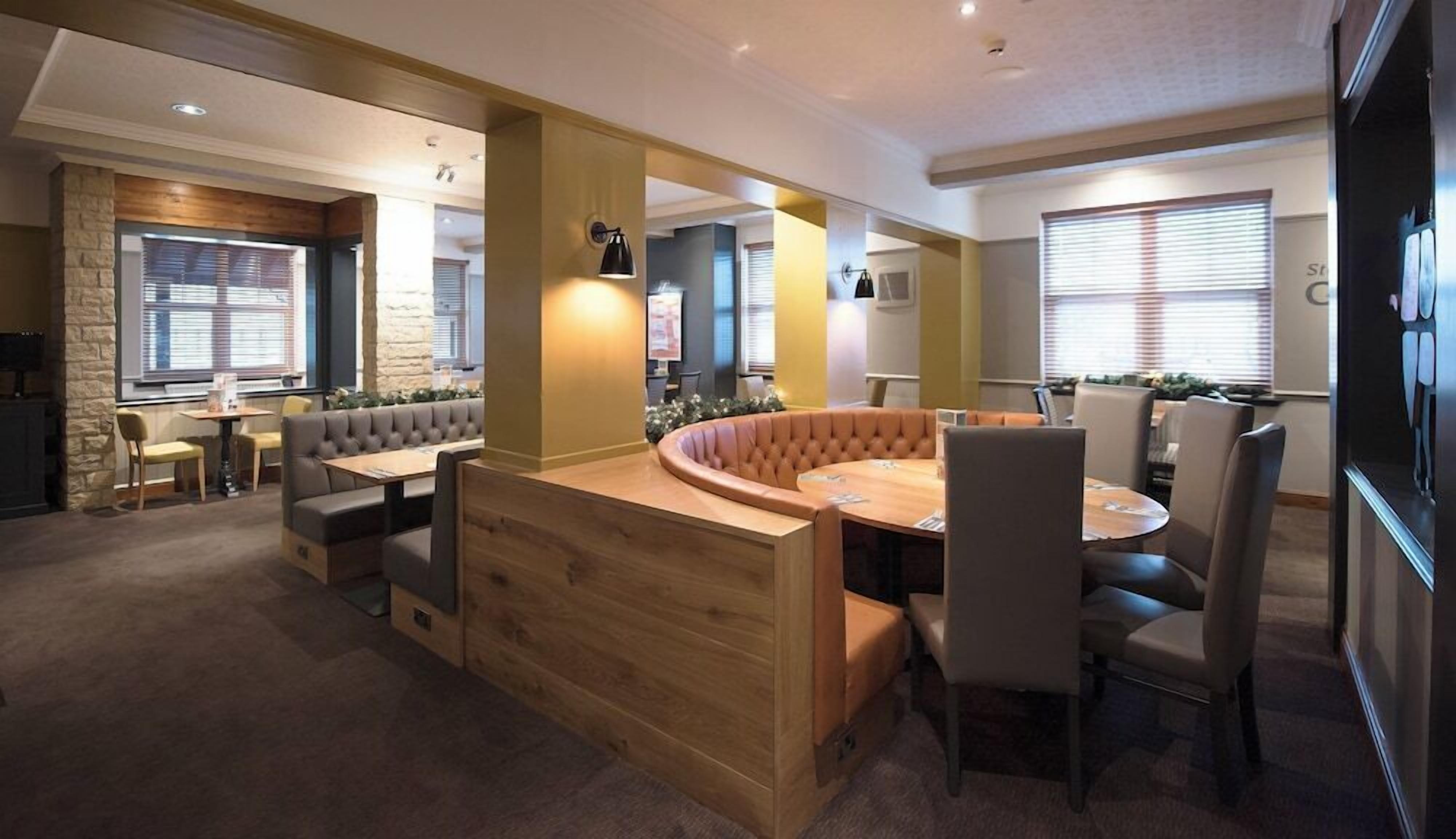 A modern interior with a central seating area, a dining table, and a kitchen in the background.
