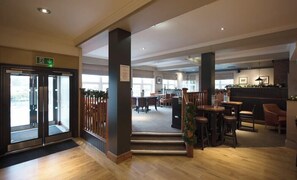 A hotel lobby with a reception desk, seating area, and a staircase leading to another floor. - Premier Inn Glasgow Hotel (Hamilton)