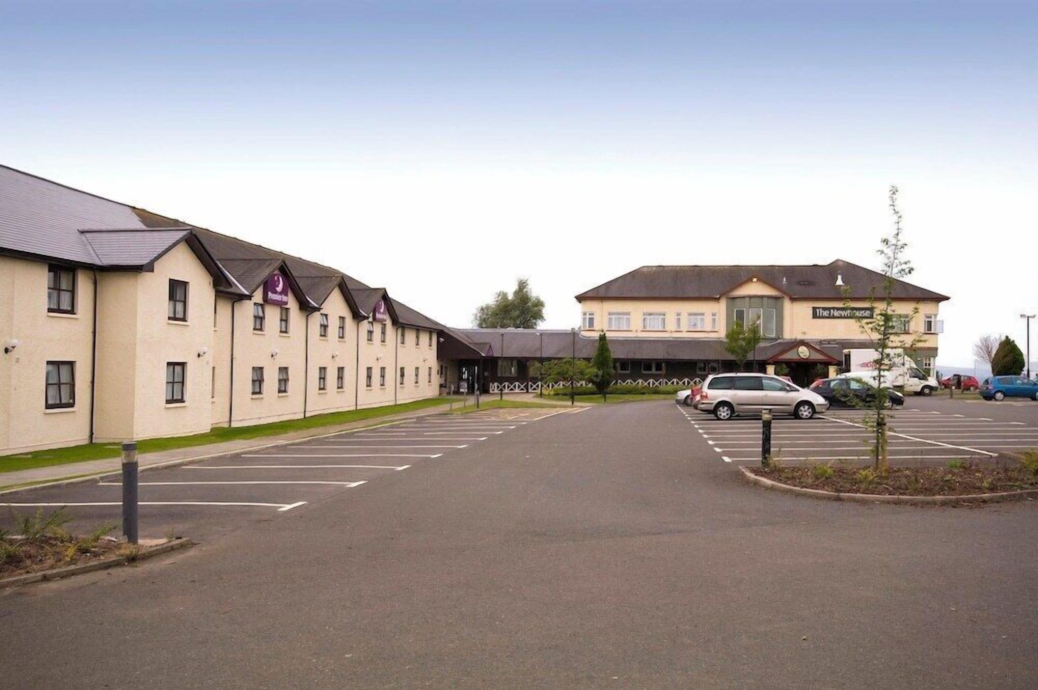 A hotel with a parking lot and a building labeled 'The Newhouse.'