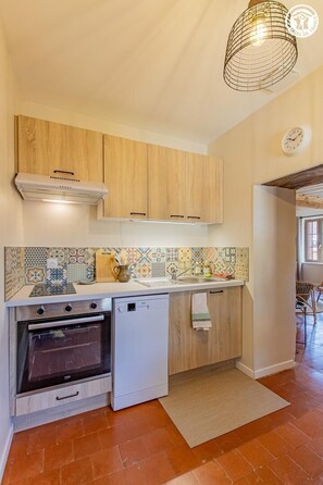 A kitchen with wooden cabinets, a tiled backsplash, a built-in oven, and a hanging light fixture. - Gîte du Promeneur - CUSSY EN MORVAN (CUSSY EN MORVAN)