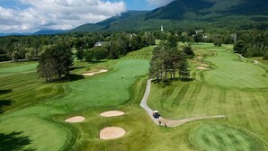 En golfbane med bunkers, et flag og et bjerg i baggrunden.