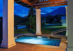 Un'area piscina con un pergolato, colonne e vista su una montagna.