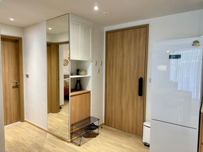 Eine moderne Küche mit Kühlschrank, Holzschränken und Schuhregal.