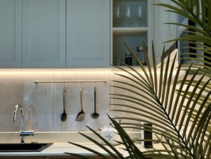 Eine Küche mit modernem Design, inklusive Spüle aus Edelstahl, Dunstabzugshaube und einer Arbeitsplatte mit Pflanze.