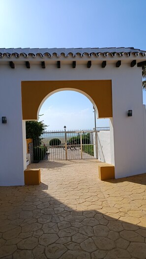 A gated entrance with a tiled roof, a paved pathway, and a view of the beach. - Sun & Beach Apartment 805 (Province of Málaga)