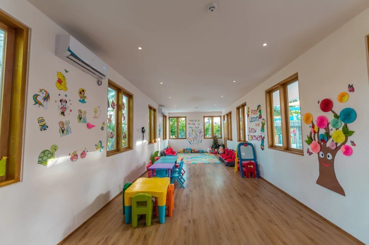 Un aula con decoraciones coloridas, piso de madera y ventanas grandes.