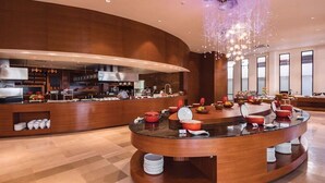 Un espace moderne dédié au petit-déjeuner, doté d’un îlot central, d’un buffet et d’un grand lustre.