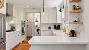 A modern kitchen with white cabinetry, a large island, and stainless steel appliances. - Lavender Porch by Avantstay Designer Bungalow + Fire Pit Near Downtown, Paso (Paso Robles)
