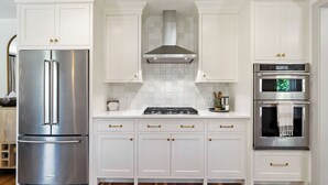 A kitchen with white cabinetry, a stainless steel refrigerator, a gas stove, and a built-in oven. - Lavender Porch by Avantstay Designer Bungalow + Fire Pit Near Downtown, Paso (Paso Robles)