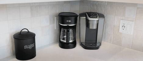 A kitchen with a coffee maker, a sugar container, and a power outlet.