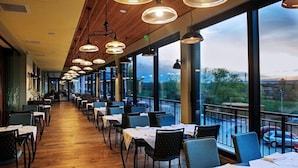 En restaurang med en lång bardisk, flera bord och hängande taklampor.