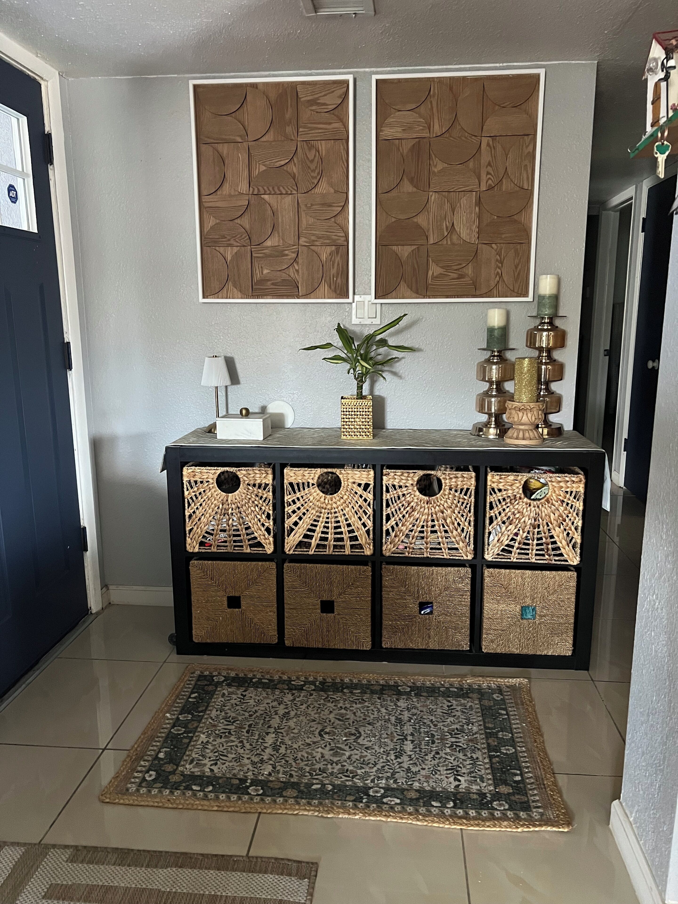 A hallway with a decorative console table, a woven rug, and a wall-mounted artwork.