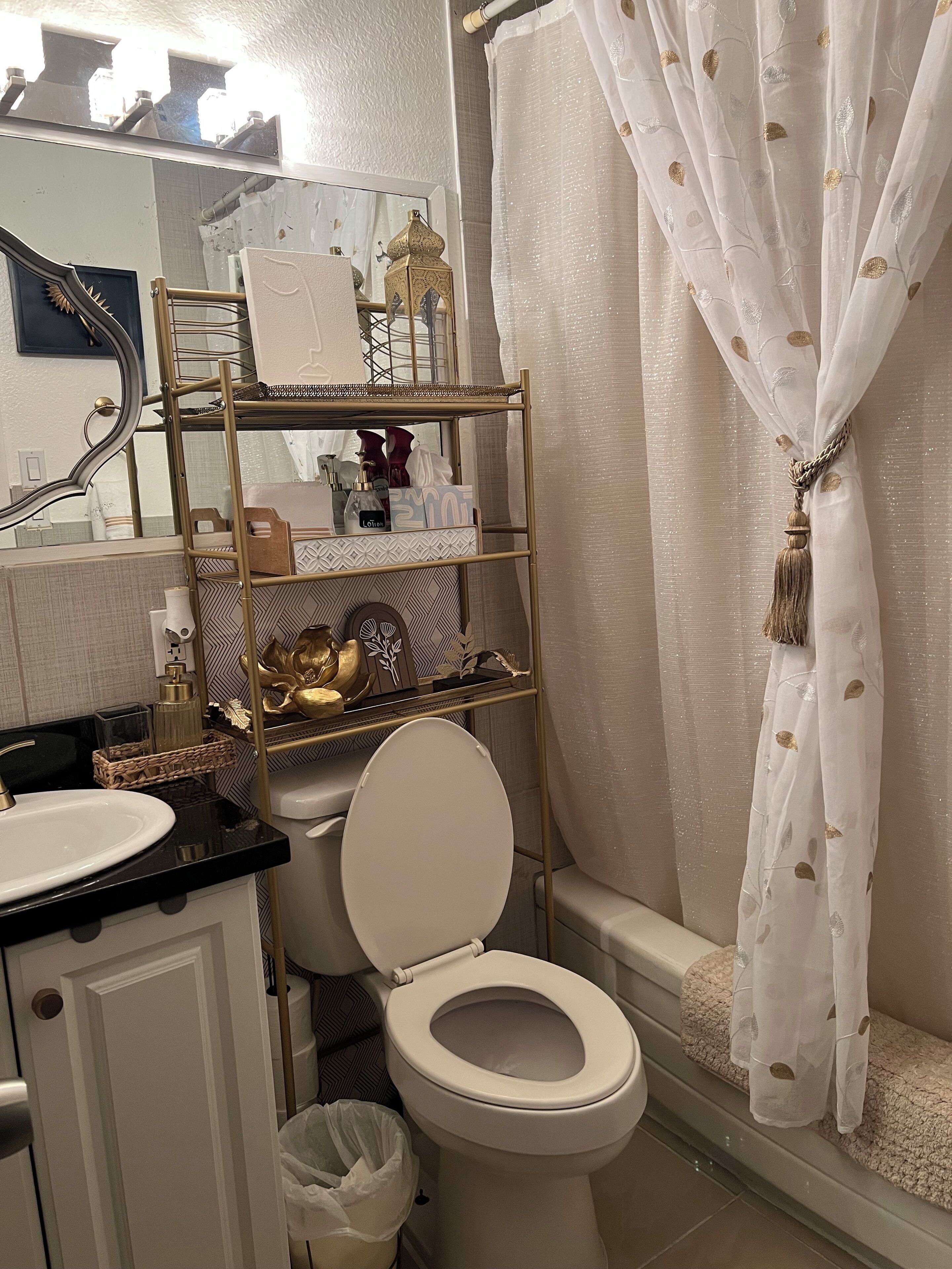 Ein Badezimmer mit Toilette, Waschbecken, Waschtisch, Duschvorhang und einem Ablagefach für Pflegeartikel.