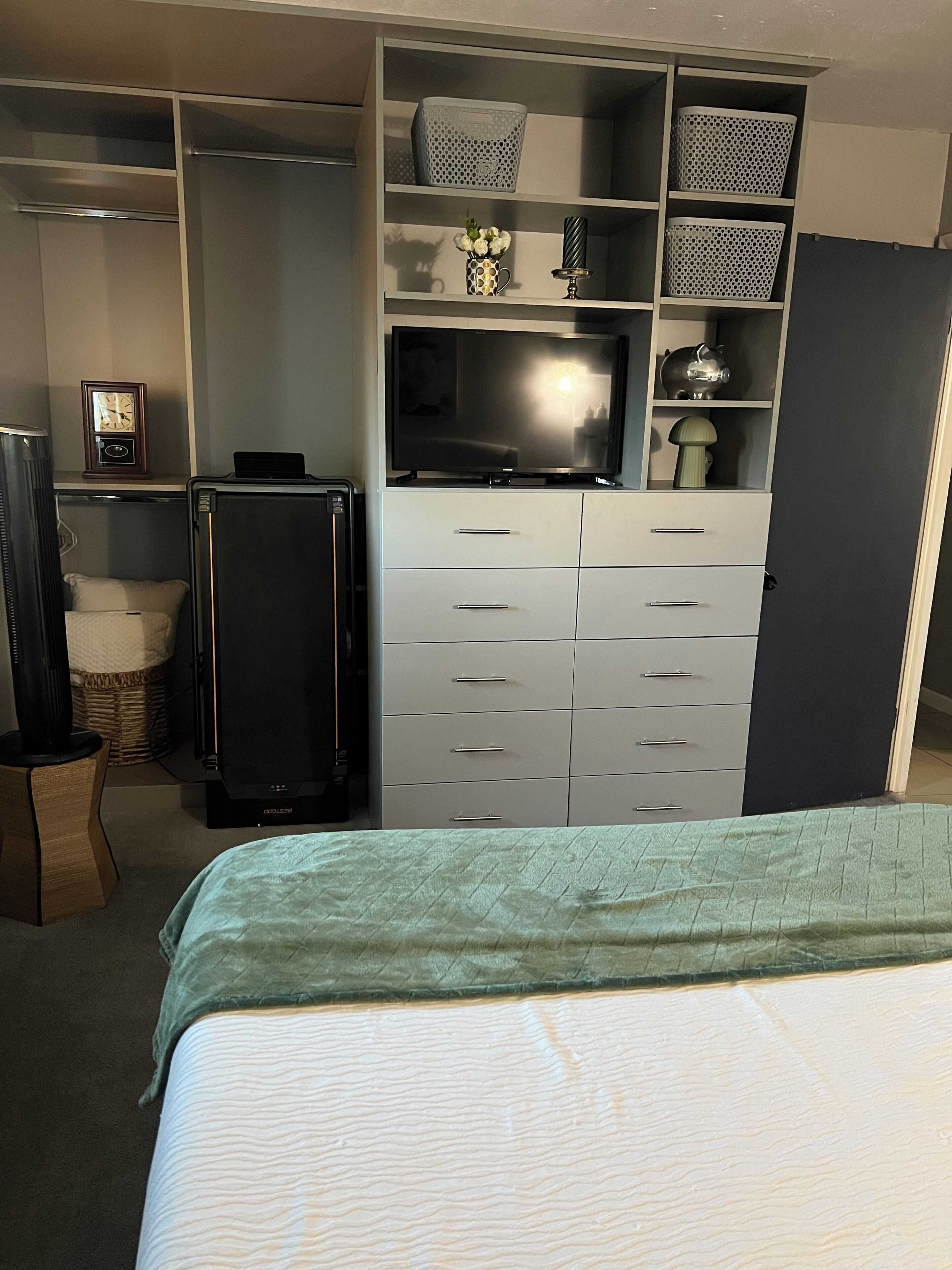 A bedroom with a bed, a television, a wardrobe, and a desk with a computer.