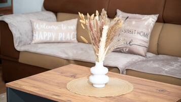 Un tavolo di legno con un vaso bianco contenente piante essiccate, posizionato su un sottotavolo intrecciato.