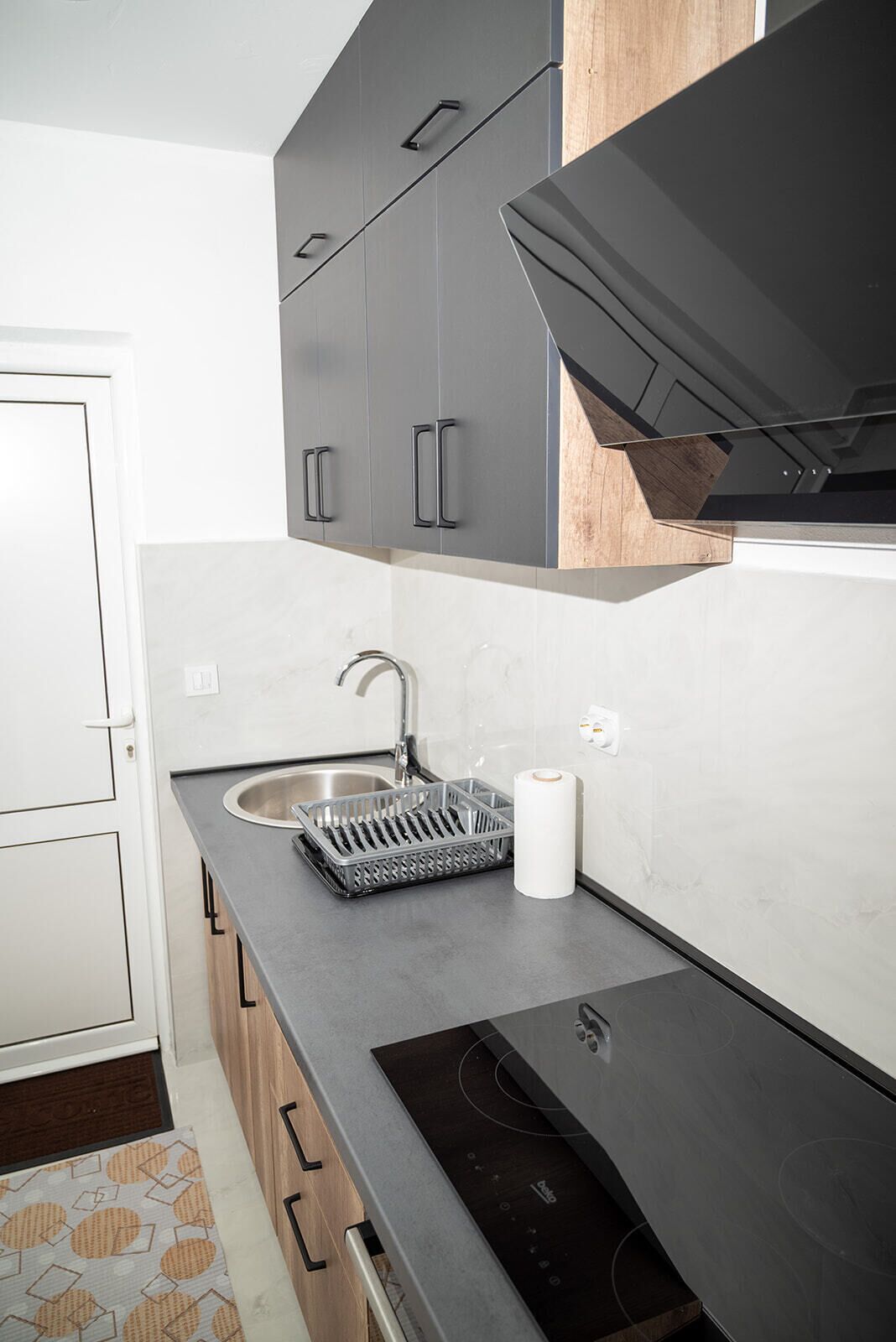 Una cocina moderna con armarios grises, un lavamanos de acero inoxidable y una cocina de inducción negra.