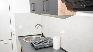 Una cocina moderna con armarios grises, un lavamanos de acero inoxidable y una cocina de inducción negra.