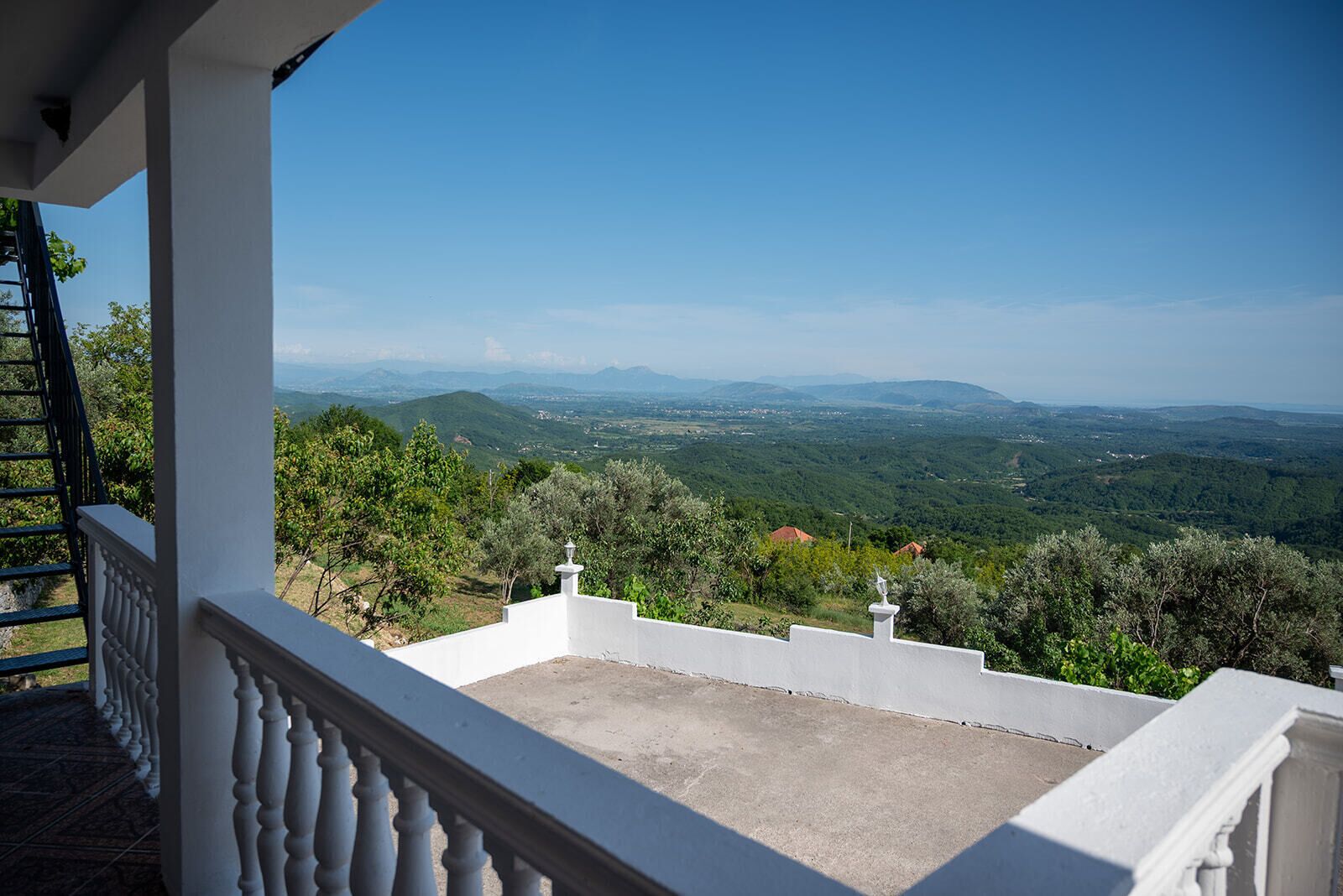 Ein Balkon mit Blick auf eine hügelige Landschaft.