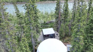 A geodesic dome structure surrounded by dense forest and a river. - Luxury Riverside Dome with Private Bathroom Near Bragg Creek (Calgary)