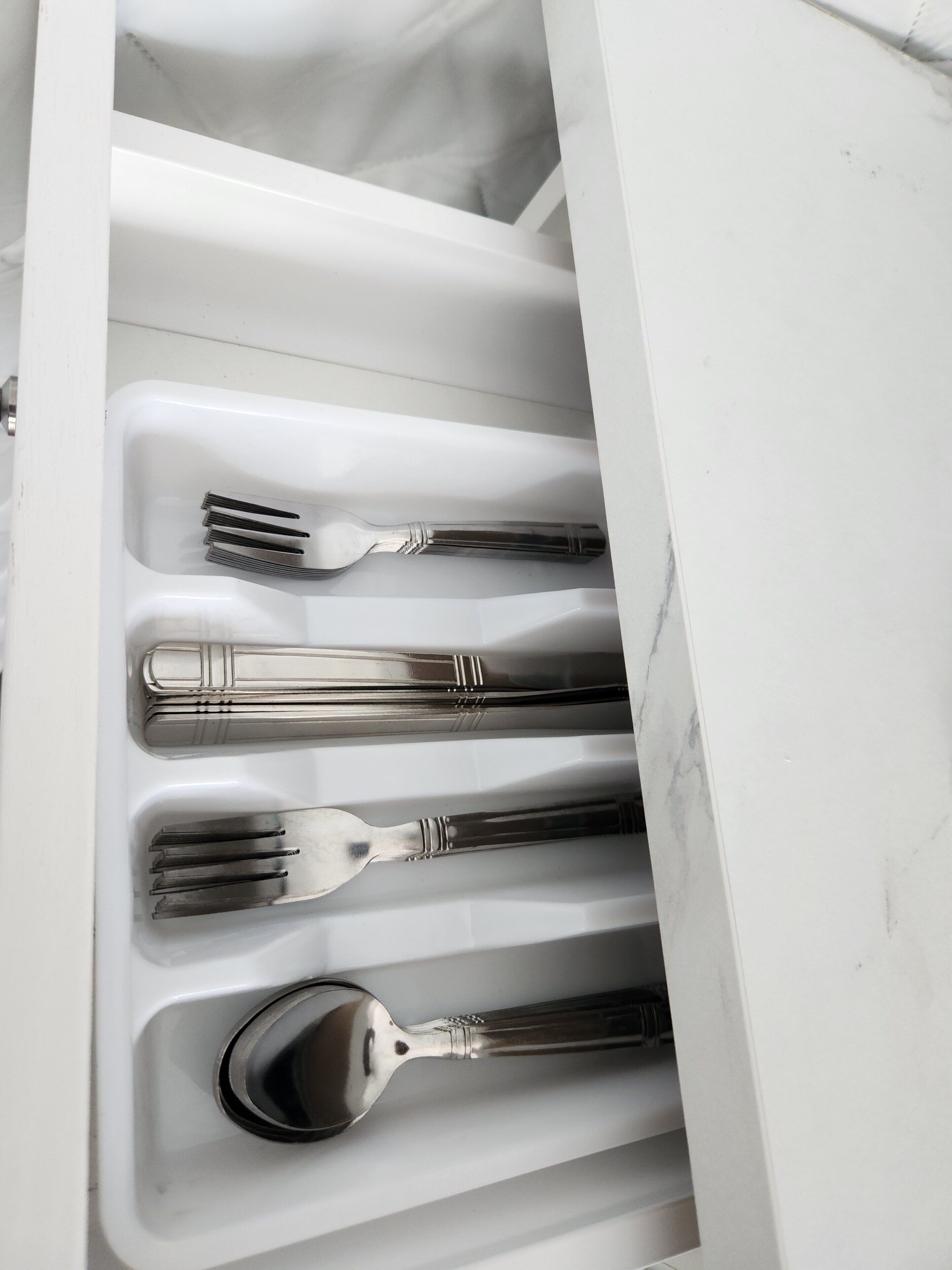 Un tiroir contenant des couverts bien rangés, notamment des fourchettes, des cuillères et des couteaux.