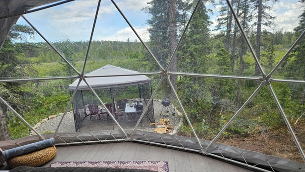 A geodesic dome structure with a view of an outdoor area including a covered seating area and a fire pit. - Luxury Riverside Dome with Private Bathroom Near Bragg Creek (Calgary)