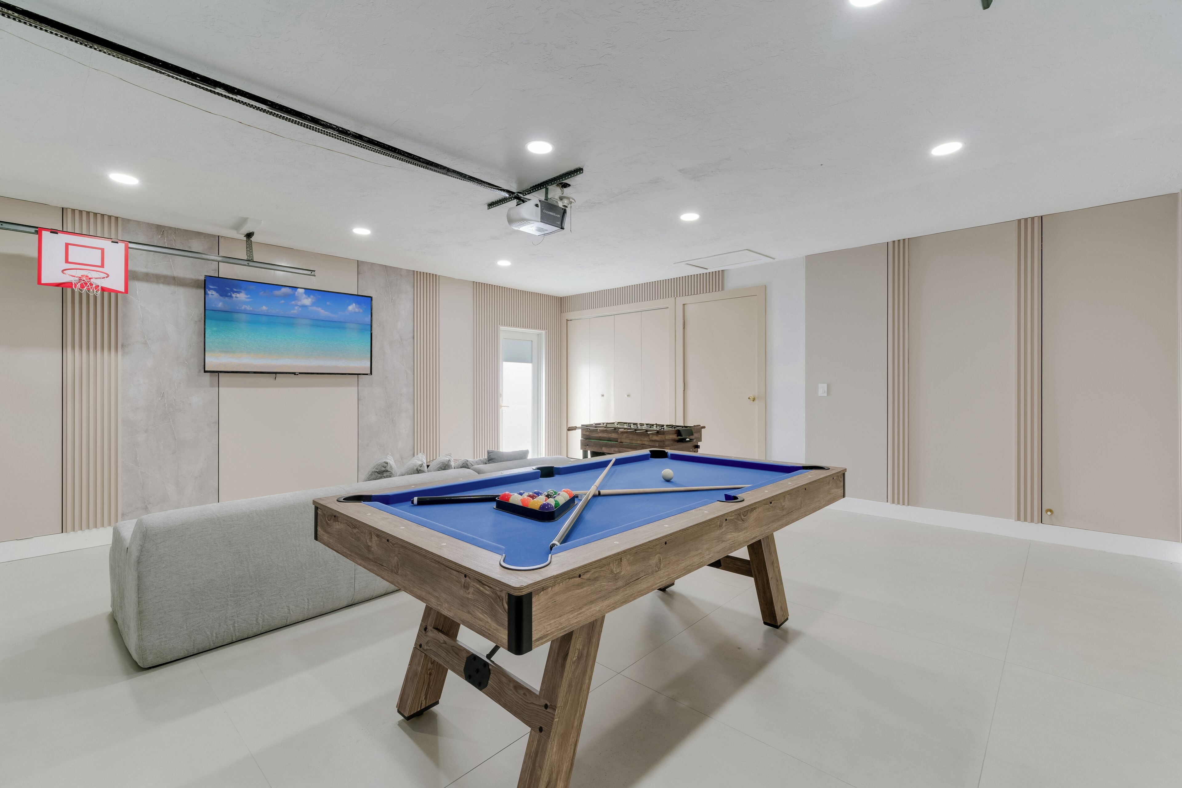 Une table de billard recouverte d’un drap bleu, un queue de billard et un jeu de billes.