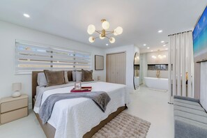 Ein modernes Schlafzimmer mit einem großen Bett, Nachttischen, einer Nachttischlampe, einem gerahmten Bild, einer roten Ablage und einem flauschigen Teppich.