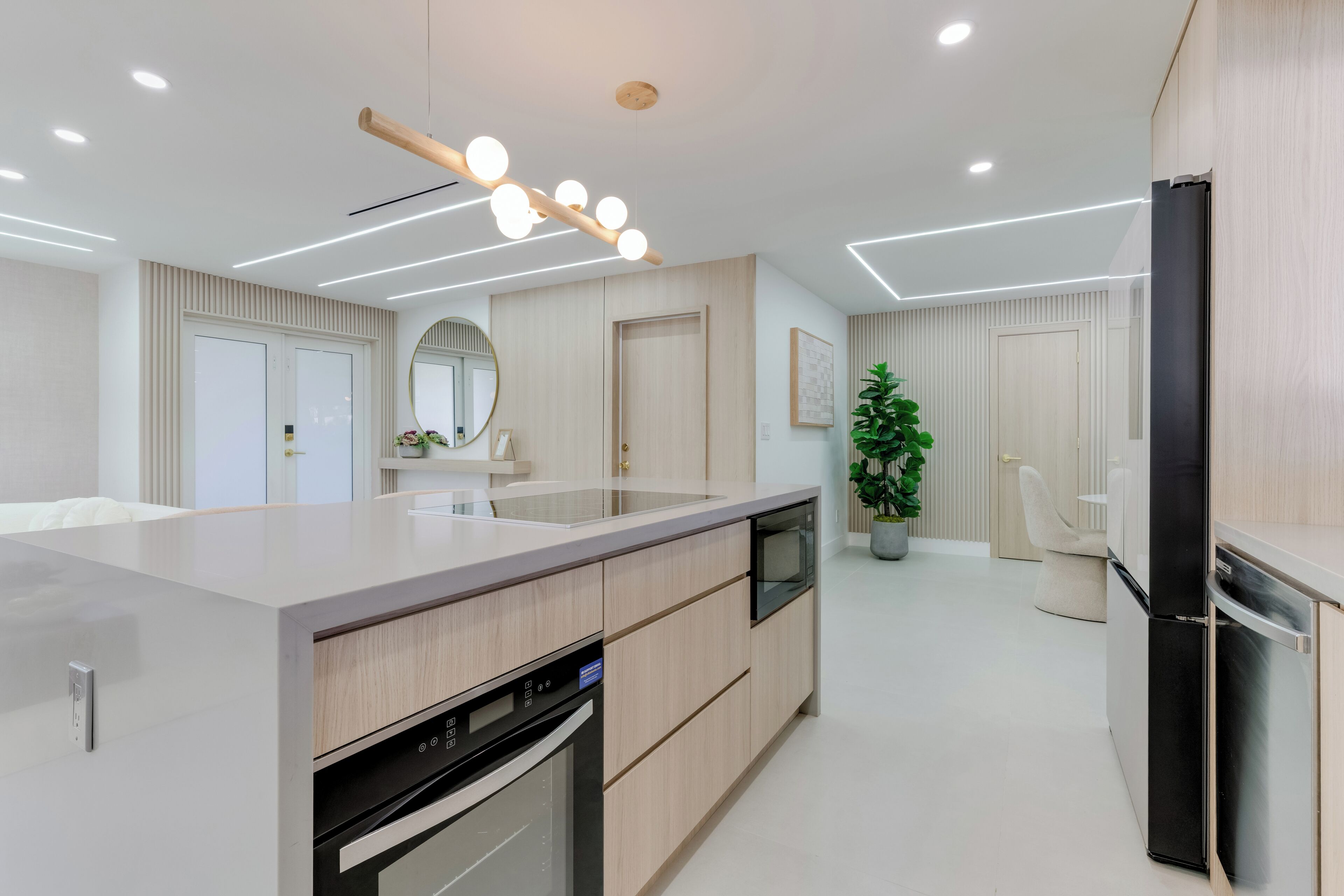 A modern kitchen with a central island, built-in oven, and a refrigerator.