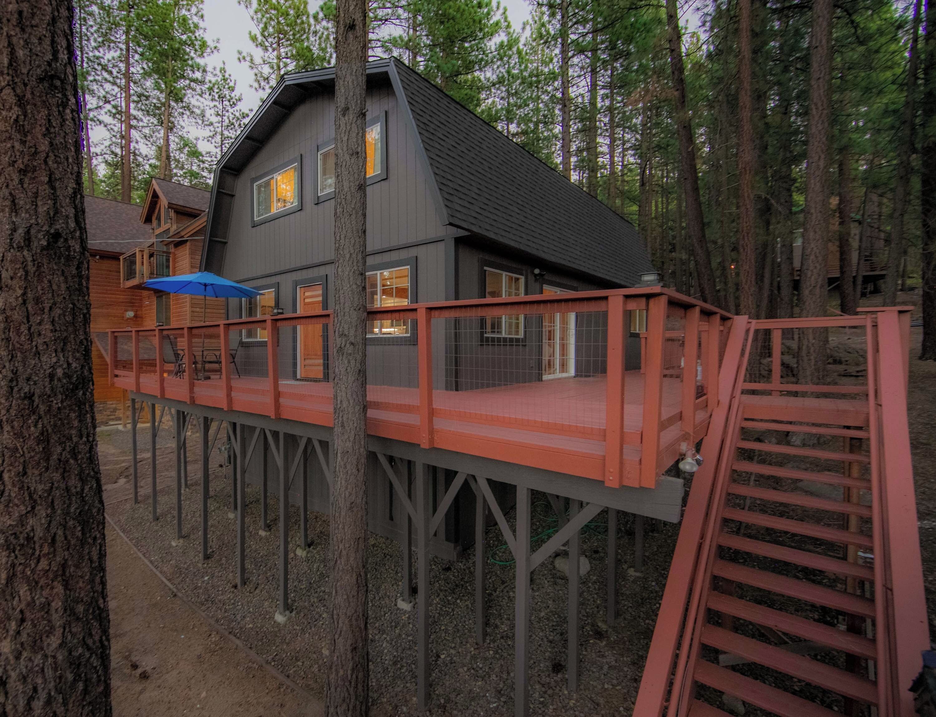 A cabin with a deck and a staircase leading to a second level.