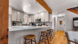 Una cocina moderna con gabinetes blancos, una isla central con taburetes, microondas y cafetera.