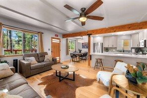 A spacious living area with a ceiling fan, a dining table, and a kitchen area with white cabinets. - Tree Top Verdon - 5bdr With Sauna (South Lake Tahoe)
