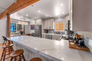 A modern kitchen with a marble island, stainless steel appliances, and a view of the outdoors. - Tree Top Verdon - 5bdr With Sauna (South Lake Tahoe)