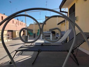A rooftop terrace with a metal table and chairs, surrounded by buildings. - Il Piccoloalbergo (Matera)