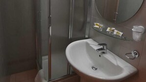 Een badkamer met een douchecabine van glas, een wastafel en een spiegel.