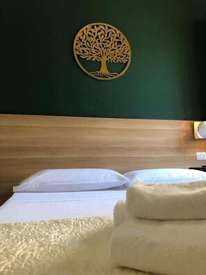 A neatly made bed with white linens and a tree-shaped wall decoration. - Il Piccoloalbergo (Matera)