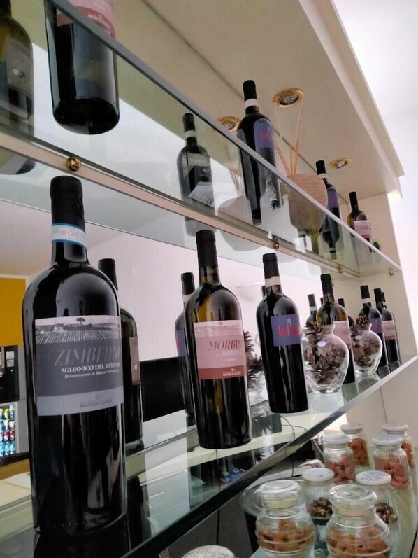 A wine rack with bottles and glass jars of dried flowers. - Il Piccoloalbergo (Matera)
