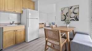 Una cocina moderna con armarios de madera, un refrigerador blanco y un comedor con mesa y sillas.